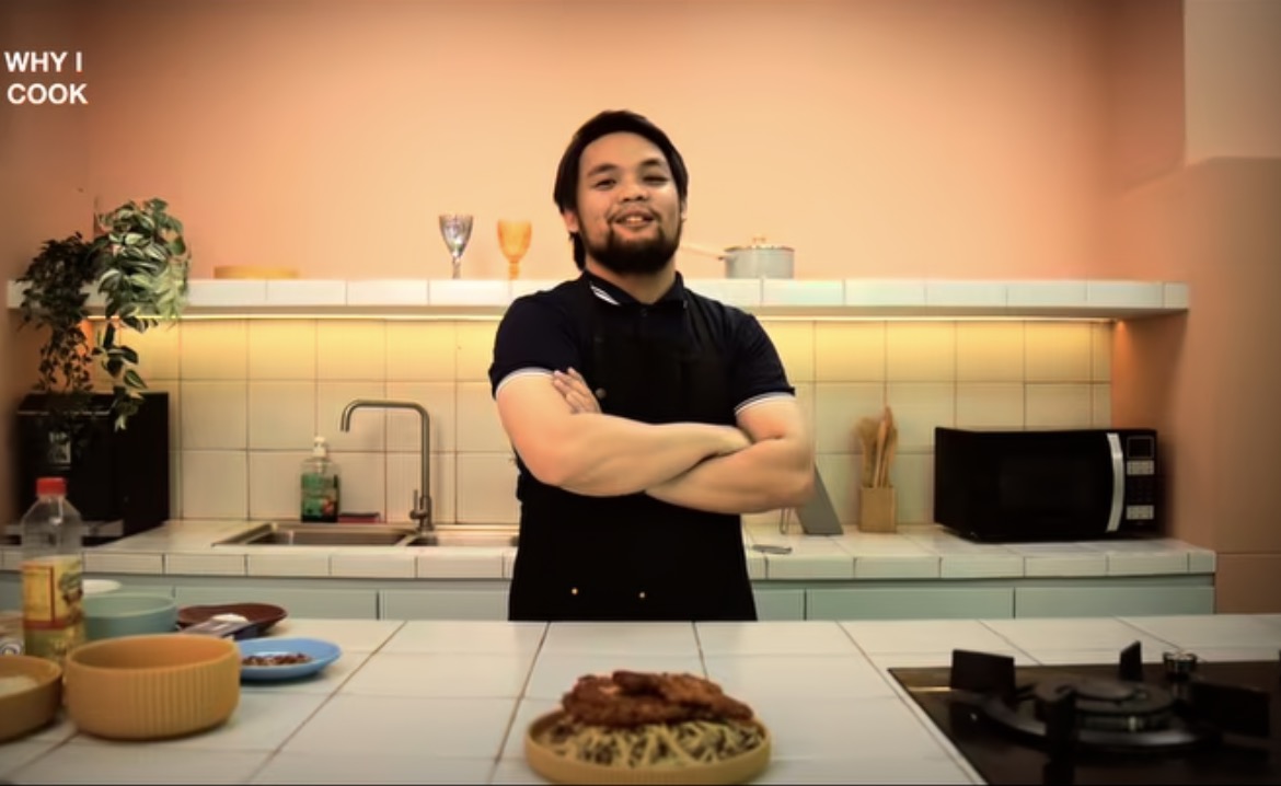 Cook standing in a warm kitchen with a prepared meal