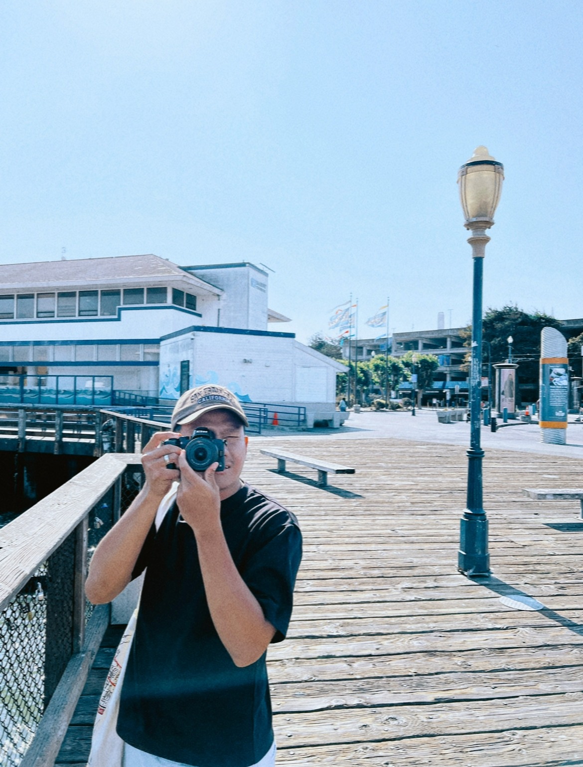 Joseph Ariono photographing on a sunlit boardwalk